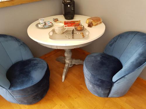 einem Tisch mit zwei blauen Stühlen und einem Tisch mit einem Tisch und einem Tisch mit einer Tabelleteryasteryastery in der Unterkunft La Marlottine in Bourron-Marlotte