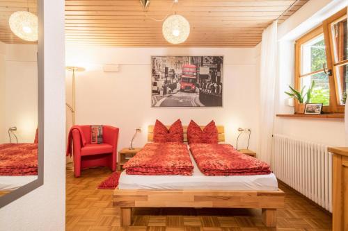 a bedroom with a bed and a red chair at Haus Sonnenschein Gartentraum in Bermatingen