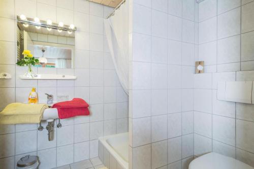 a white bathroom with a tub and a toilet at Haus Sonnenschein Gartentraum in Bermatingen