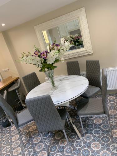 a white table with chairs and a vase of flowers at Luxury Lakeside Living Broadview 2 Georgian Town House in Enniskillen
