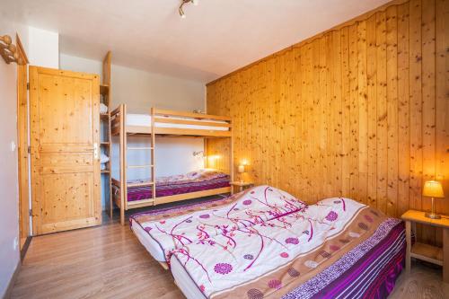 1 Schlafzimmer mit 2 Etagenbetten und einer Holzwand in der Unterkunft Cellier n3 in Les Deux Alpes