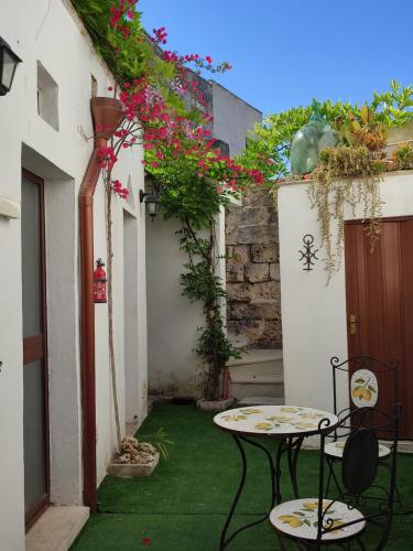 un patio con 2 sillas, una mesa y flores en La Dimora della nonna Rosina, en Galatone