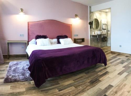 a bedroom with a large bed with a purple bedspread at La Casona de Alútiz & Bodega in Samaniego