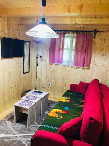 een woonkamer met een rode bank en een tafel bij Etno domacinstvo Stankovic apartman br 2 in Gornji Milanovac