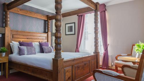 um quarto com uma cama de dossel em madeira com almofadas roxas em Muthu Clumber Park Hotel and Spa em Worksop
