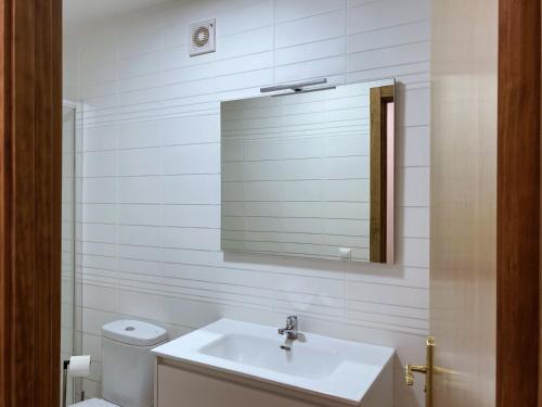Baño blanco con lavabo y espejo en Casa Senagüilla en Robledillo de Gata