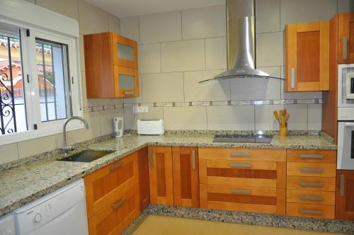 a kitchen with wooden cabinets and a sink at 2021 PRICES!! FAMILY VILLA BY MARINA private pool heating optional, snooker in Benalmádena