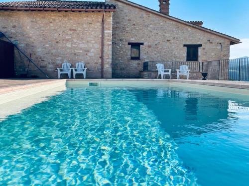 een zwembad met witte stoelen en blauw water bij Agriturismo I CASALI DI MORRO in Sellano