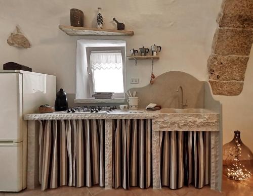 een keuken met een aanrecht met een wastafel en een koelkast bij I Trulli dell'Orfanello in Martina Franca