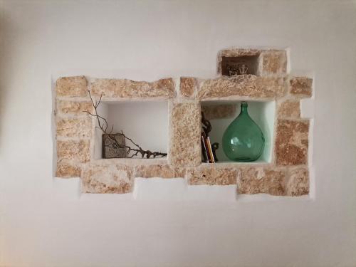 een stenen muur met een groene vaas erop bij I Trulli dell'Orfanello in Martina Franca