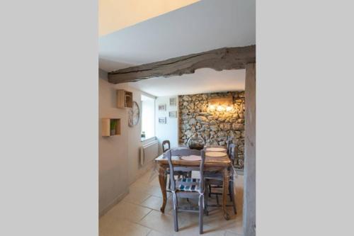 une salle à manger avec une table et des chaises et un mur en pierre dans l'établissement Les chemins du Mont, à Lortet
