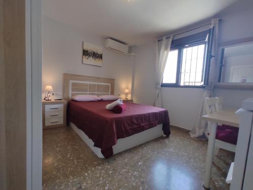 1 dormitorio con 1 cama con colcha roja y ventana en Villa Patricia, en Málaga