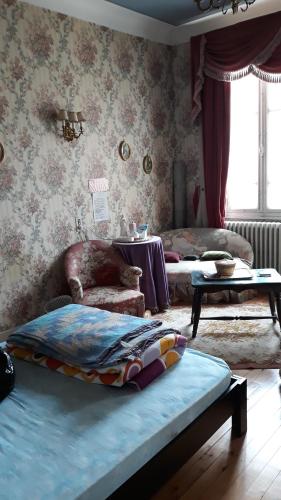 a bedroom with a bed and a chair and a table at Chez Virginie in Lourdes