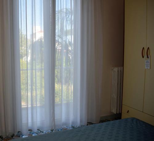 a bedroom with a large window with white curtains at Hotel Casa Di Meglio in Ischia
