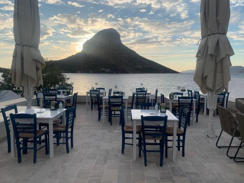 ein Restaurant mit Tischen und Stühlen mit einem Berg im Hintergrund in der Unterkunft La Playa Boutique Apartments in Kalymnos