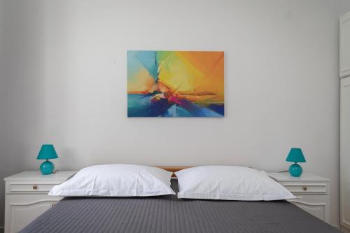 a bed with two pillows and a painting on the wall at Apartman Rakic in Makarska