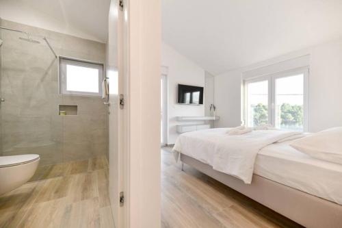 a white bedroom with a bed and a bathroom at NEW Villa Buterin with heated pool in Novigrad Dalmatia