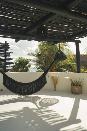 a hammock on a patio with palm trees at NEST Tulum in Tulum