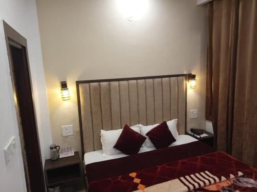 a bedroom with a bed with red and white pillows at The Divine Oak in Katra