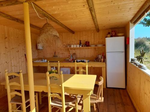 a kitchen with a wooden table and a refrigerator at Quintal Alentejano in Zambujeira do Mar