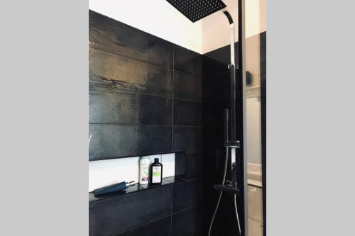 y baño con ducha y pared de azulejos negros. en Mazzini apartment en Arona
