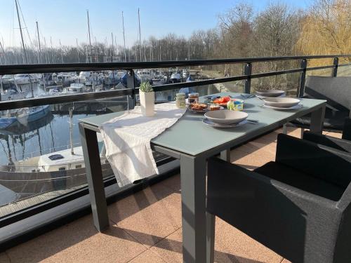 a table with food on a balcony with a marina at Näher am Wasser kann man nicht wohnen! in Arnemuiden