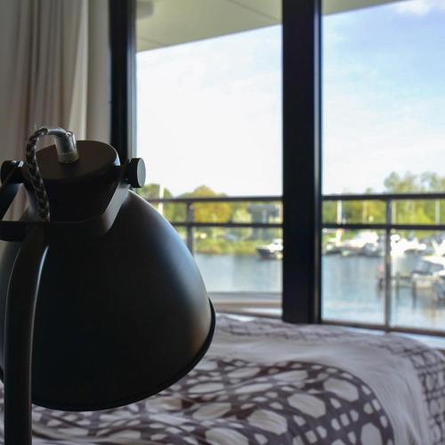 a lamp sitting on a bed in front of a window at Näher am Wasser kann man nicht wohnen! in Arnemuiden