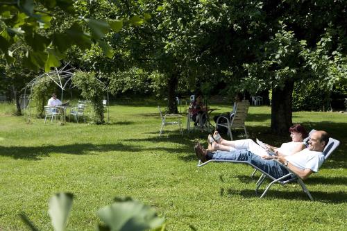two people sitting in lawn chairs in a park at Parkhotel Emmaus - Casa del Sole in Ascona