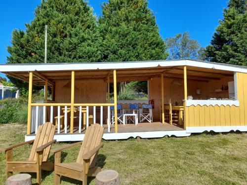 a small yellow house with a porch and two chairs at Quintal Alentejano in Zambujeira do Mar