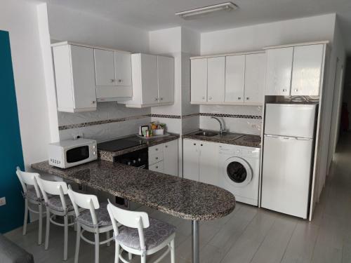 une cuisine avec des placards blancs et un comptoir avec des appareils blancs dans l'établissement Almi Cabezo appartamento con terrazza El Médano, à El Médano