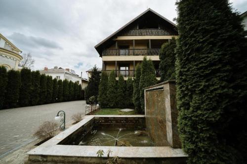 une maison avec une fontaine en face d'un bâtiment dans l'établissement Vila CLASS, à Vatra Dornei