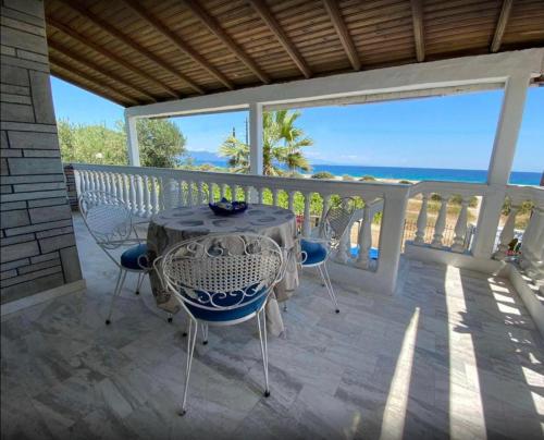 Ikidiki Beach Villa في إيريسوس: طاولة وكراسي على شرفة مع المحيط