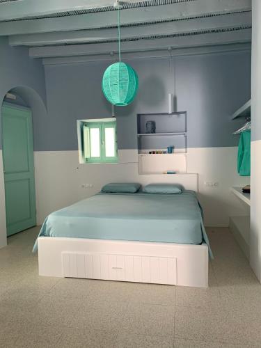a white bedroom with a bed with a blue blanket at IANUA Casa per Viaggiatori in Astypalaia