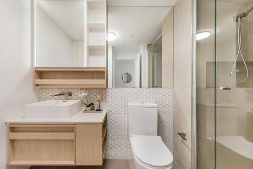 a bathroom with a toilet and a sink and a shower at Chic 1-Bed with City Views, Parking, Gym & Pool in Melbourne