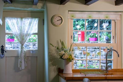 a kitchen with a window and a clock on the wall at Poppy Cottage in Grassington