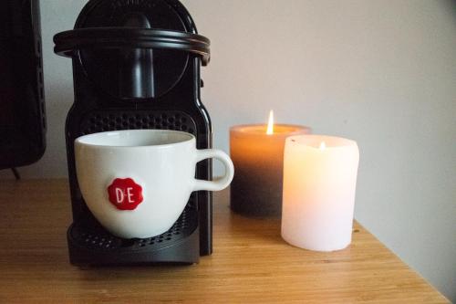 PERFECT B&B MIDDLE OF AMSTERDAM في أمستردام: كوب قهوة وشمعة على طاولة