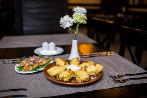 a table with two plates of food and a vase with flowers at Chalet Carpat Dream in Synevyr