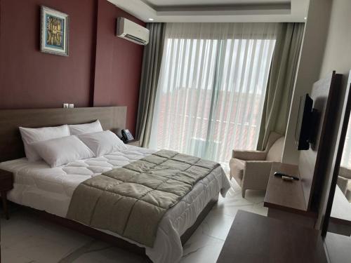 a bedroom with a bed and a large window at RESIDENCE SYCOMORE 1 in Abidjan