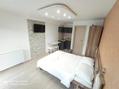 a bedroom with a white bed and a stone wall at Studio Dunja in Soko Banja