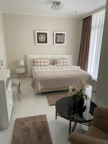 a white bedroom with a bed and a table at Residence Puro Beach - Adults only in Międzyzdroje
