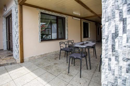 eine Terrasse mit Stühlen, einem Tisch und einem Fenster in der Unterkunft Brize Guesthouse in Tuzla