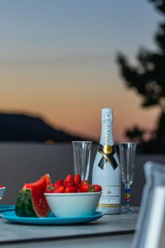 a table with a bowl of fruit and a bottle of wine at Rainbow Apartments in Stalida