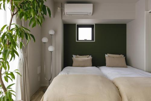 2 camas en una habitación con una pared verde en THREE - Vacation STAY 38687v, en Tokio