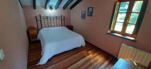 a bedroom with a bed with white sheets and two windows at El Caserío in Camaleño