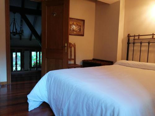 a bedroom with a white bed and a wooden floor at El Caserío in Camaleño