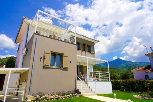 a white house with a balcony and mountains in the background at Charikleia's 2 bedroom appartment in Pelion in Volos
