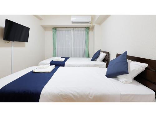 two beds in a hotel room with a tv at HOTEL Nishikawaguchi Weekly - Vacation STAY 44797v in Saitama
