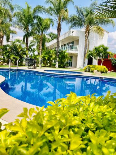 a swimming pool in front of a building with palm trees at Hotel Cascada in Cuautla Morelos