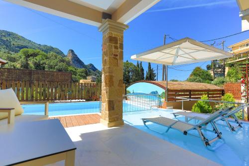 a patio with a table and a chair and an umbrella at Villa Kadith Agios Gordios in Agios Gordios