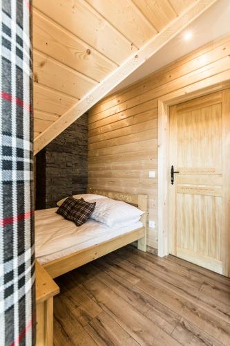 a room with a bed in a wooden cabin at Domki Tatrzański Przystanek in Białka Tatrzanska